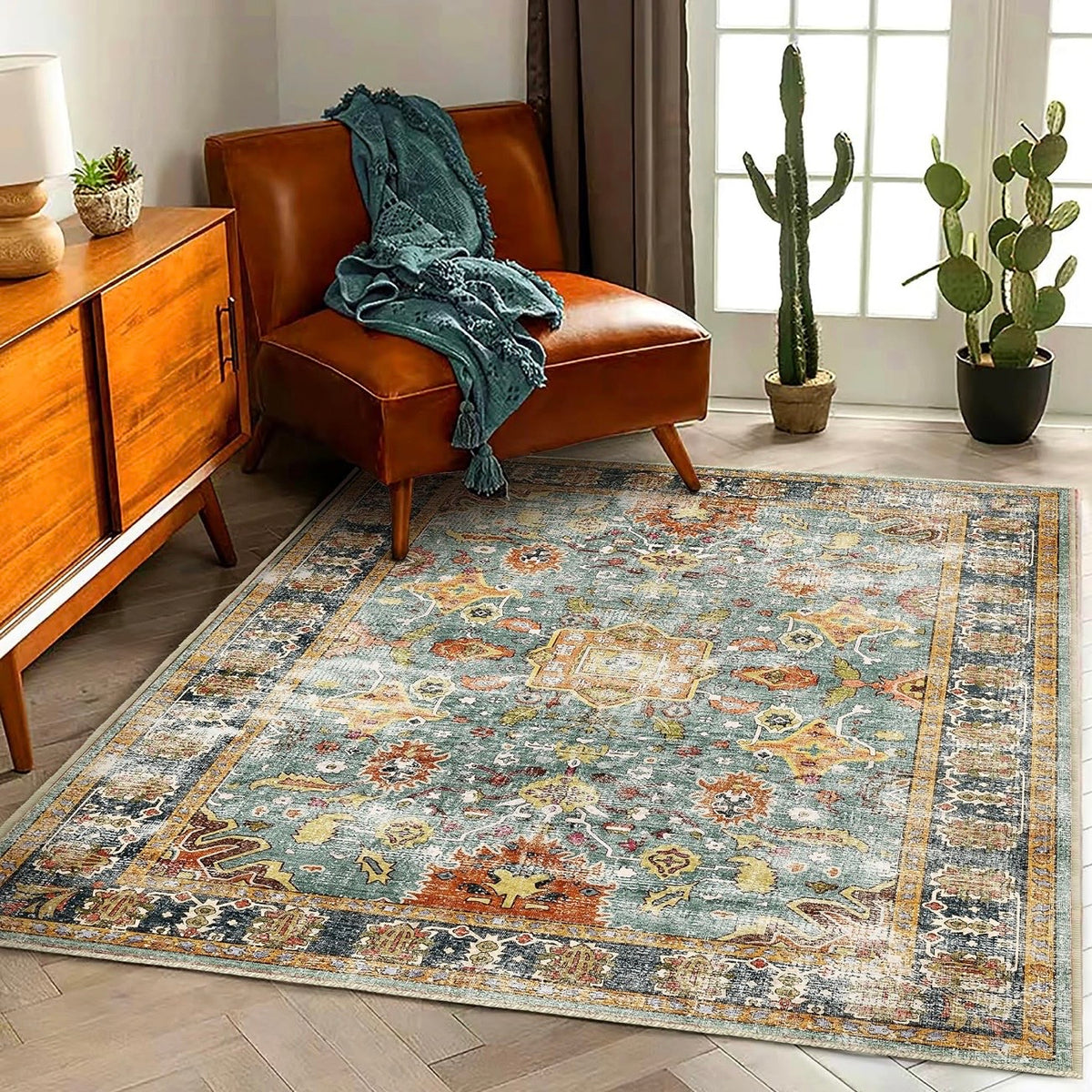Blue Moroccan floral boho area rug with intricate vintage patterns in teal and orange, styled under a leather chair and cacti.